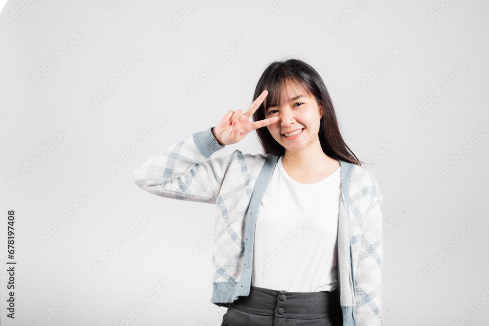 Woman showing finger making v-sign victory symbol near eye looking to camera, Happy Asian beautiful young female mark peace gesture symbol, studio shot isolated on white background with copy space Woman showing finger making v-sign victory symbol near eye looking to camera, Happy Asian beautiful young female mark peace gesture symbol, studio shot isolated on white background with copy space