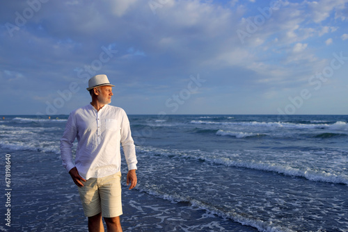 Handsome man in white shirt and hat on seashore