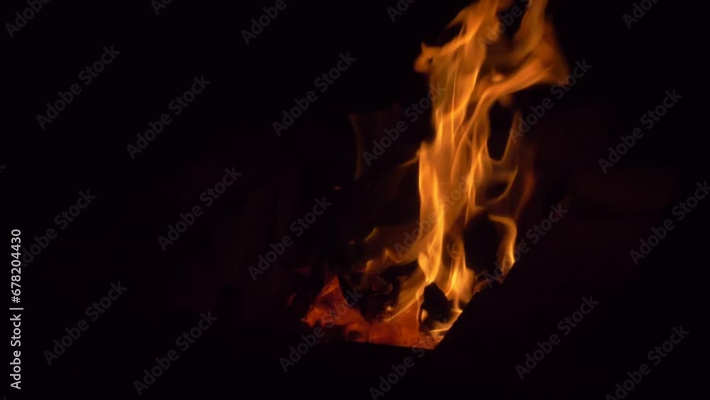 Slow motion. Hot coals in a fire and a bright fire in the complete darkness of the night. Slow motion. Hot coals in a fire and a bright fire in the complete darkness of the night.
