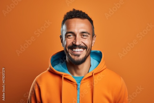 Portrait of a smiling man in his 30s wearing a zip-up fleece hoodie against a solid color backdrop. AI Generation © CogniLens