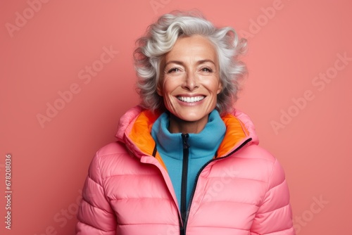 Portrait of a cheerful woman in her 60s sporting a quilted insulated jacket against a solid color backdrop. AI Generation