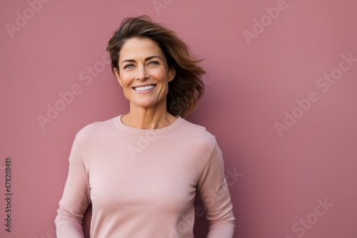Portrait of a smiling woman in her 40s showing off a thermal merino wool top against a solid pastel color wall. AI Generation