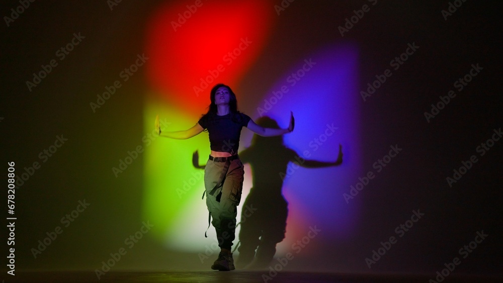 Attractive woman in top and black pants posing at camera dancing jazz funk in studio, isolated on red green blue neon background. Attractive woman in top and black pants posing at camera dancing jazz funk in studio, isolated on red green blue neon background.