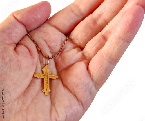 Cross on a chain in the palm of a man's hand on a white background.