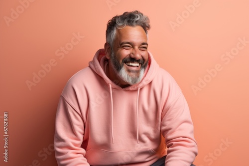 Portrait of a happy man in his 50s sporting a comfortable hoodie against a solid pastel color wall. AI Generation