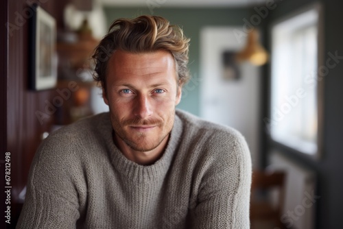 Portrait of a grinning man in his 30s dressed in a warm wool sweater against a scandinavian-style interior background. AI Generation
