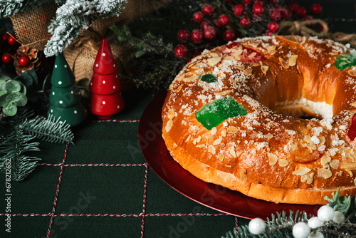Fotografie Roscon de reyes with cream on a red plate and christmas ornaments