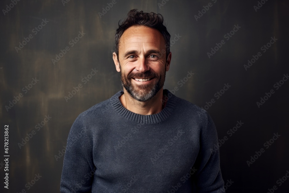 Portrait of a grinning man in his 40s dressed in a warm wool sweater against a bare concrete or plaster wall. AI Generation