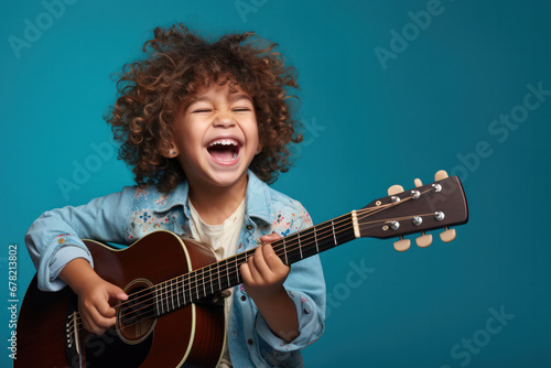 Musical Delight, Happy Child Strumming a Guitar with Joy on Blue Background