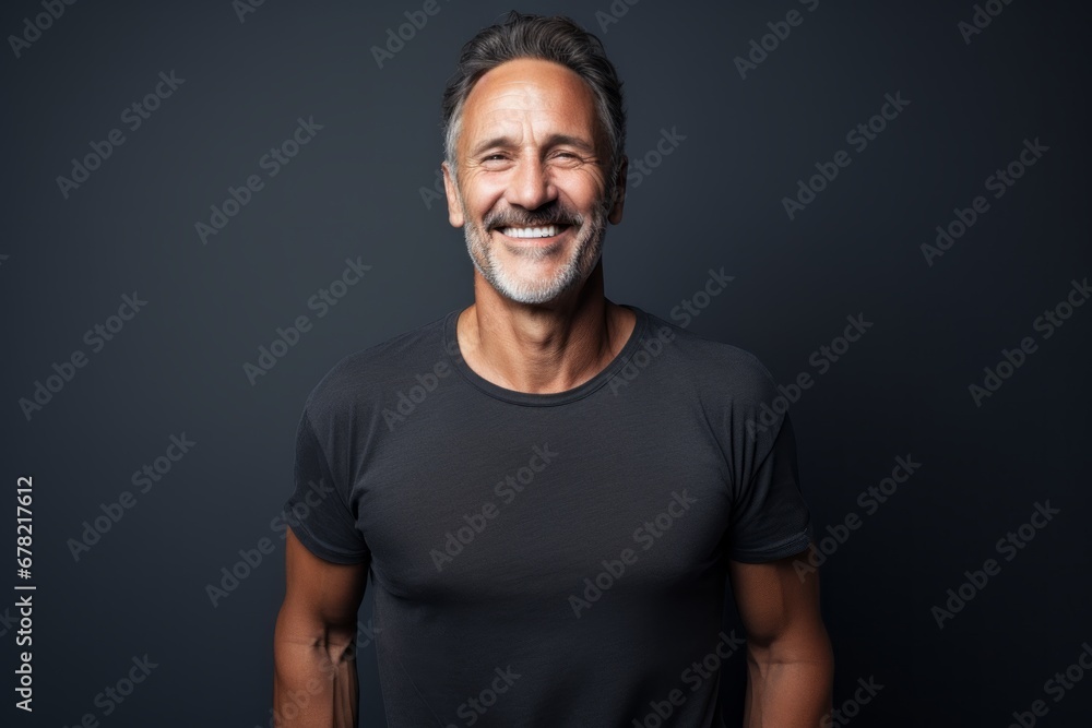 Portrait of a smiling man in his 50s dressed in a casual t-shirt against a bare monochromatic room. AI Generation