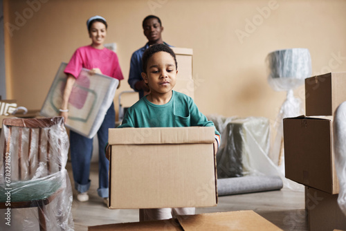Canvas Print Cute little boy carrying packed cardboard box and putting it on top of another o