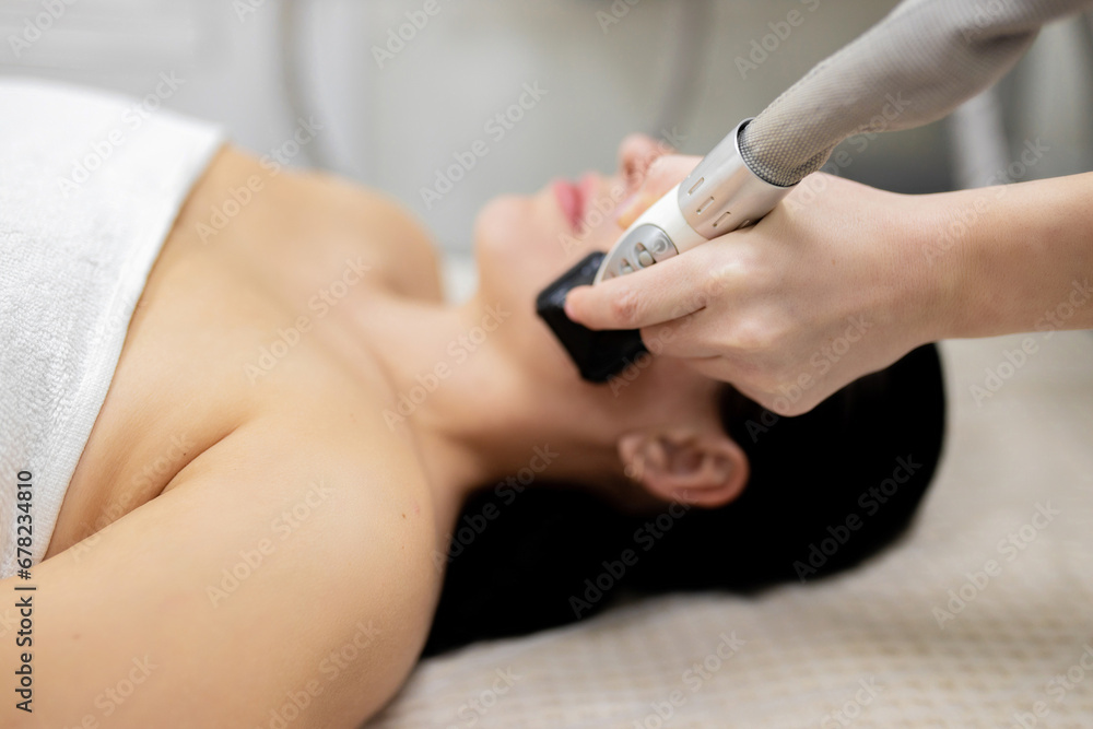 Microneedle RF lifting procedure. Hardware cosmetology. Beautician conducts a facial rejuvenation procedure for a brunette woman Microneedle RF lifting procedure. Hardware cosmetology. Beautician conducts a facial rejuvenation procedure for a brunette woman