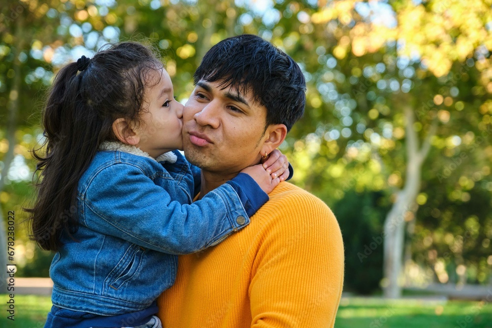 Portrait of happy Ecuadorian son kissing his father in a park. Portrait of happy Ecuadorian son kissing his father in a park.