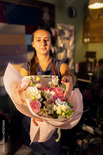 Young woman working in her flower shop holding bouquet.