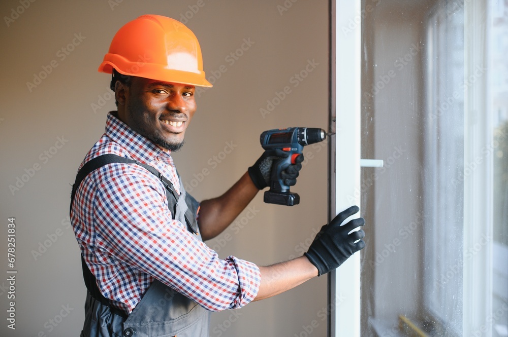 handsome young african american man installing bay window in new house construction site handsome young african american man installing bay window in new house construction site
