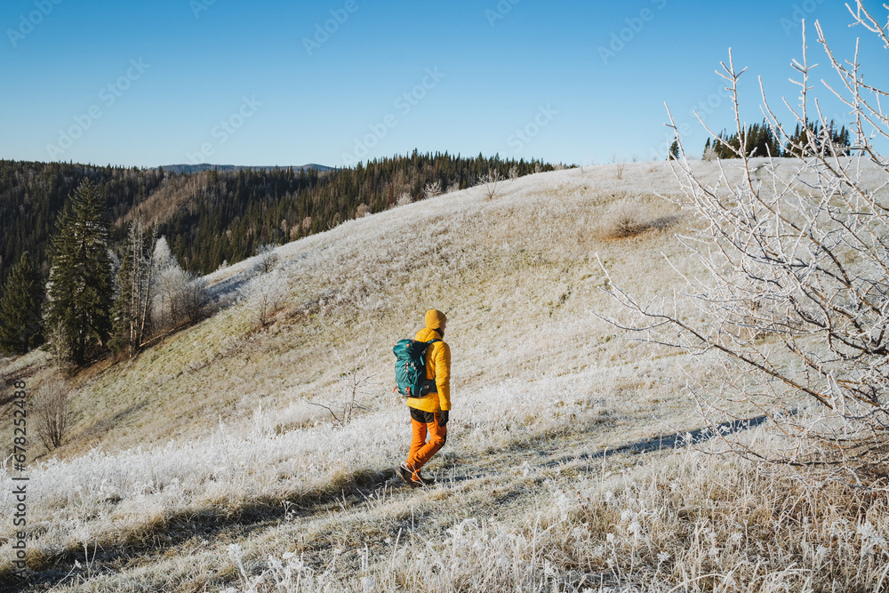 Winter hiking in the mountains, a man walks with a backpack on a snowy road, vacation in the mountains, beautiful landscape, frost on the ground. Winter hiking in the mountains, a man walks with a backpack on a snowy road, vacation in the mountains, beautiful landscape, frost on the ground.