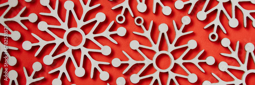 Pattern of wooden snowflakes on a red background. Banner