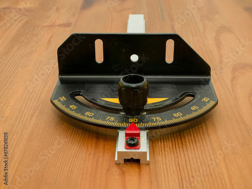 Close up of a table saw mitre gauge with engraved angle scale, pointer  and T bar track attachment  on a wooden background photo