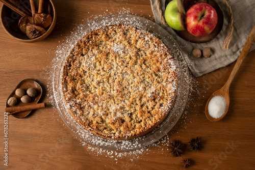 Schilderij op canvas Top view of an apple crumble pie on a wooden table with cinnamon and apples in t