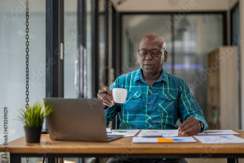 Wallpaper Mural A black senior man in casual clothes is on a video call while sipping coffee at the table. Torontodigital.ca