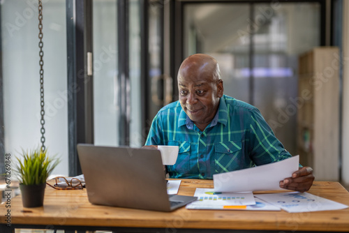 Wallpaper Mural A black senior man in casual clothes is on a video call while sipping coffee at the table. Torontodigital.ca