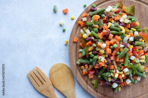 Mix of frozen vegetables on a wooden stand: carrots, corn, green peas, bell peppers, green beans, red beans. Image with copy space, horizontal orientation, top view. 