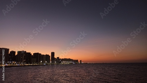 Beachfront twilight in Fortaleza; city lights and azure waves under a soft pink sky photo