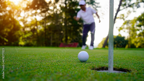 Blurred golfer playing golf in the evening golf course, on sun set evening time.