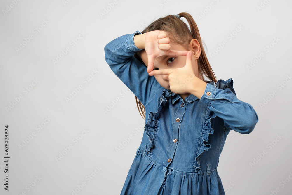 Close up of little girl showing frame with fingers over white background Close up of little girl showing frame with fingers over white background