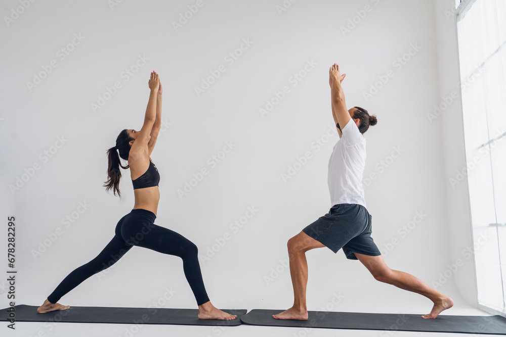 Naklejka premium Health,lifestyle and exercise concept.woman sports wear exercising with a yoga instructor man practices yoga together and poses while stretching together in a home living room