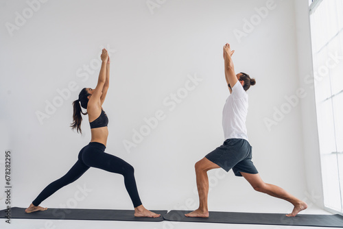 Health,lifestyle and exercise concept.woman sports wear exercising with a yoga instructor man practices yoga together and poses while stretching together in a home living room