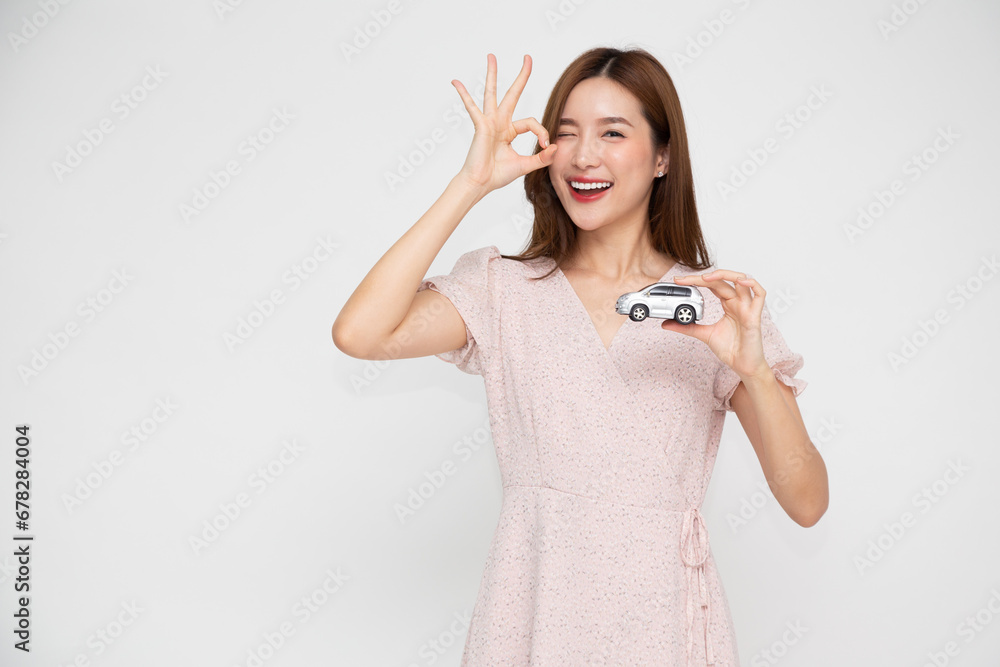 Young Asian woman holding car model isolated on white background, Travel and Motor Insurance concept Young Asian woman holding car model isolated on white background, Travel and Motor Insurance concept