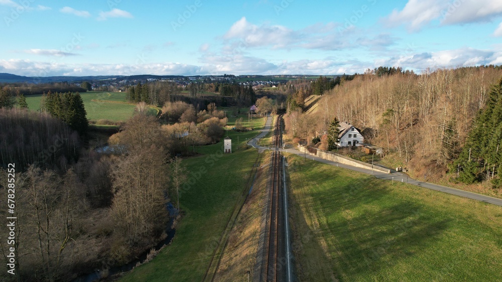 Drone shot over green fields with autumn trees at countryside on a sunny day