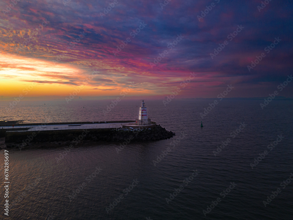 there is a lighthouse at the end of a pier at sunset