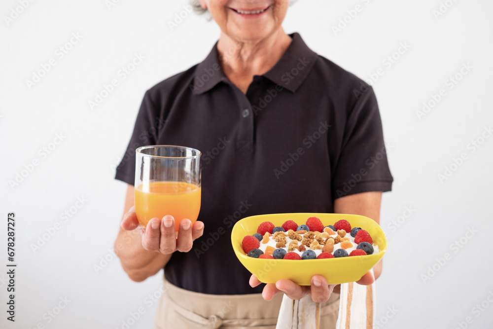 Waitress woman hands holding an orange juice and a bowl of yogurt and fresh and dried fruit with almond, raspberries, blueberries. Breakfast or lunch, healthy eating and dietary concept Waitress woman hands holding an orange juice and a bowl of yogurt and fresh and dried fruit with almond, raspberries, blueberries. Breakfast or lunch, healthy eating and dietary concept