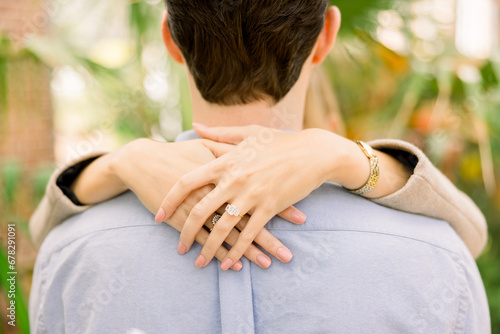 An engaged couple with the woman's hands slung over his shoulder