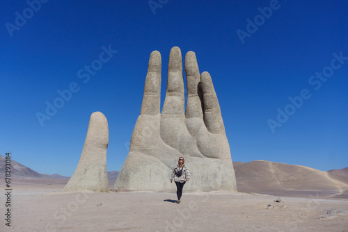 Young woman in front of the Hand of the desert in the Atacama desert, Chile