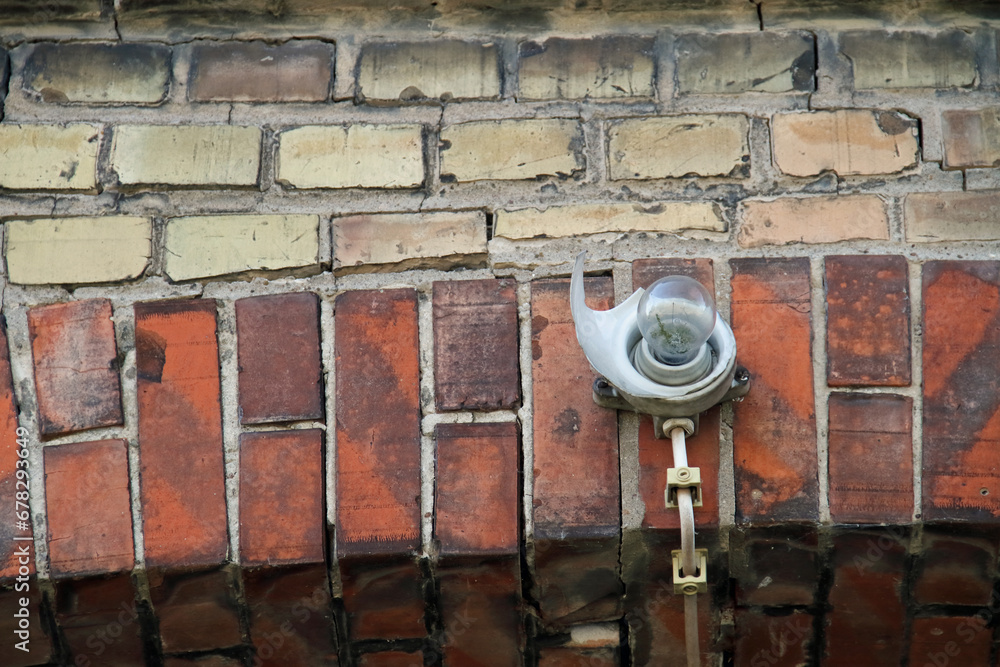 a destroyed wall lamp on an old brick wall outdoors a destroyed wall lamp on an old brick wall outdoors