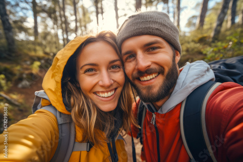 Cute romantic couple taking a selfie while hiking in a forest. Autumn season. Concept of togetherness in nature and wanderlust