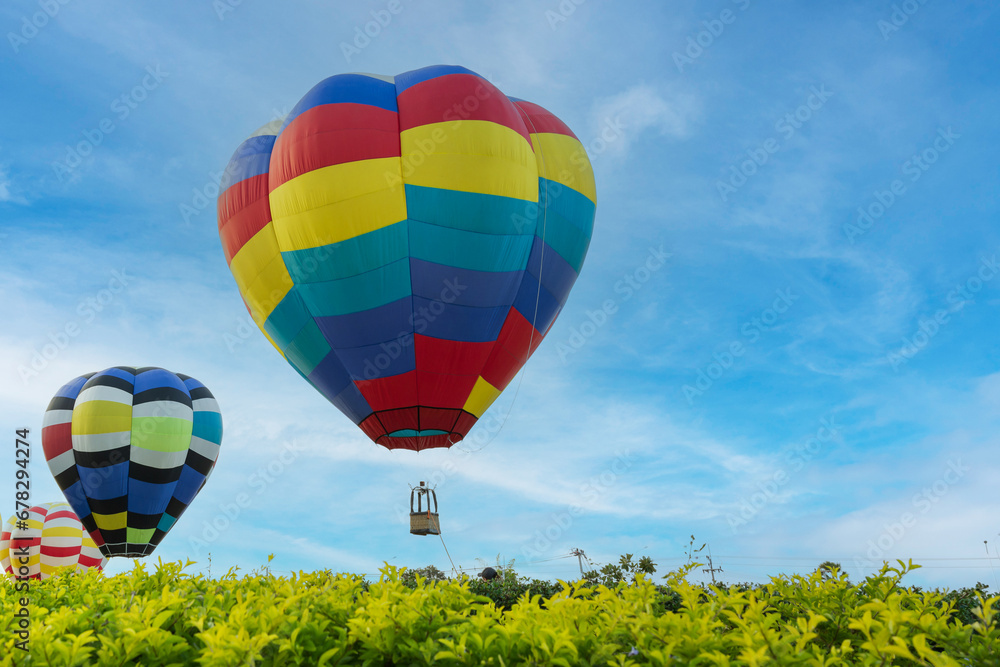 Obraz premium Colorful hot air balloons flying over green tree on blue sky background in nation park.Hot air balloon festival travel concept.