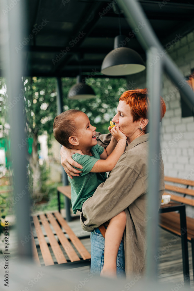 Family mother with her son holding on her hands playful mommy love enjoy time at the terrace redhead woman with short haircut Family mother with her son holding on her hands playful mommy love enjoy time at the terrace redhead woman with short haircut