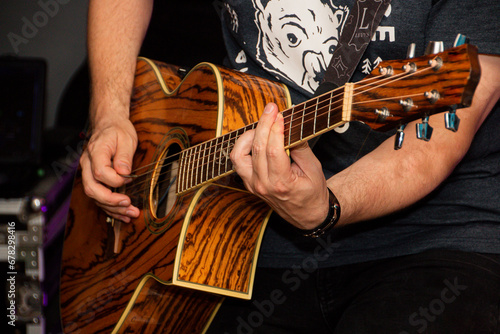 Guitarist in black t-shirt plays tiger guitar close-up