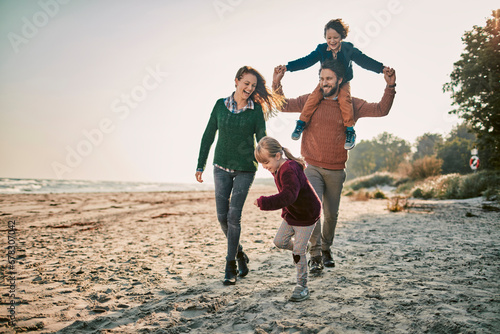 Happy family dressed in warm clothes walking on the beach