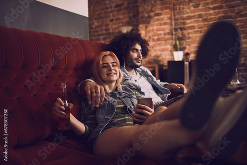 Relaxed Couple Enjoying Music and Drinks on a Cozy Sofa photo