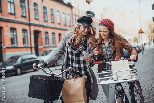 Two young Caucasian women friends shopping in town with bicycles photo