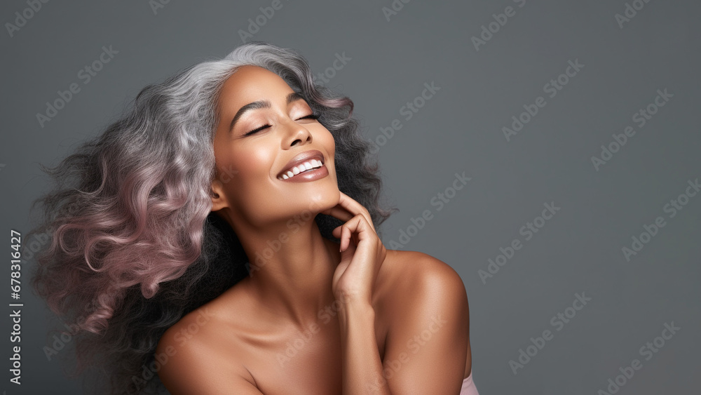 Fototapeta premium Beautiful mature woman with long gray hair and happy smiling on gray background