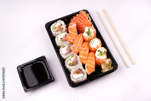 Japanese oriental food tray sushi delivery isolated on background top view angled on white background with chopsticks and soy sauce photo