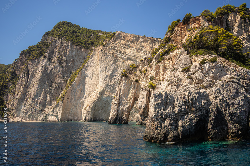 Keri Caves during Summer Day in Zakynthos. Rocky Cliff with Trees and Ionian Sea in Greece. Keri Caves during Summer Day in Zakynthos. Rocky Cliff with Trees and Ionian Sea in Greece.