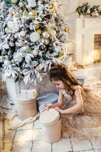 Canvas Print Little cute girl in a beautiful dress in christmas with gift boxes