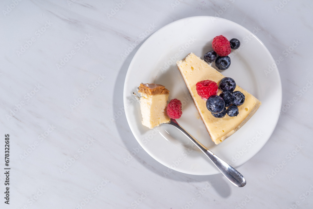 Cheesecake portion slice on plate, with raspberry on blueberry on white marble background 